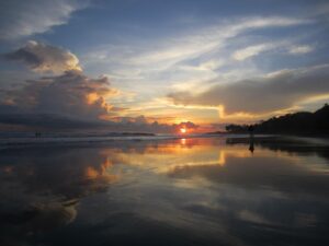 Five Days In El Salvador: Archeology, Beaches, Coffee And Mountains A mesmerizing sunset casts a golden glow over the wet sand of a beach, mirroring the sky and clouds above.