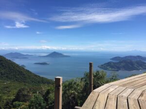 Beaches, Mountains, Coffee, Culture And Island Hopping In El Salvador (14 days) A scenic view from a wooden deck overlooking lush islands in a blue sea under a partly cloudy sky.