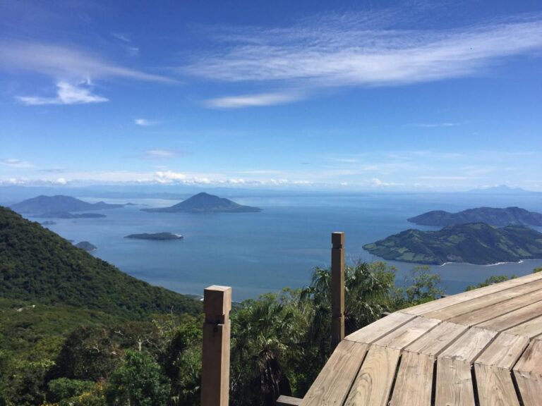 A scenic view from a wooden deck overlooking lush islands in a blue sea under a partly cloudy sky.