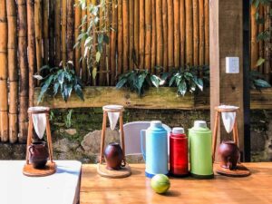 El Salvador’s Coffee History A scenic view of a wooden table setting with coffee drippers, vintage thermoses, and a lime against a bamboo wall adorned with plants.