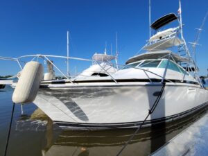 Boat Rental With Crew in El Salvador A bright, sleek white yacht with multiple decks and tall antennas is docked, reflecting in the water under a clear blue sky.