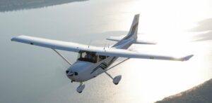 Plane Charter In El Salvador An airplane flies over a body of water with land visible in the distance.