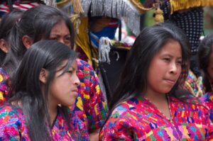 History Of El Salvador A group of young indigenous women in colorful traditional clothing stand together, looking slightly off to the side, in an outdoor setting.